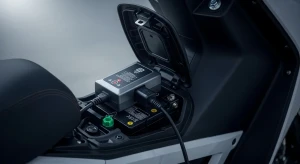 Charger motor listrik original yang sedang terhubung untuk mengisi daya baterai